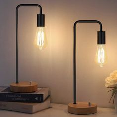 two light bulbs sitting on top of a table next to books and a vase with flowers