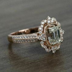 an engagement ring with a large green diamond surrounded by small white and brown diamonds on a wooden surface