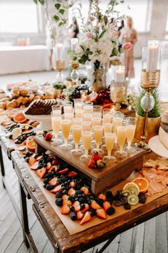 a wooden table topped with lots of glasses filled with champagne and fruit on top of it