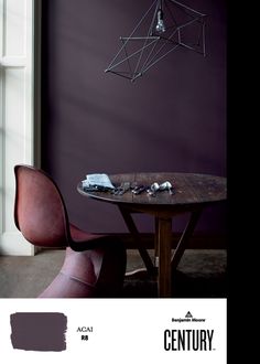 a dining room table with chairs and a purple color scheme on the wall behind it