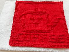 a red knitted dishcloth sitting on top of a white towel