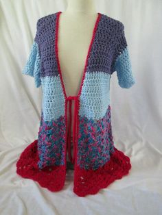 a crocheted cardigan is displayed on a mannequin