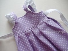 a purple dress with white polka dots is laying on the floor and ready to be sewn