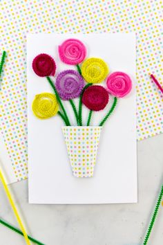 flowers in a vase with the number five on it, and some crocheted straws