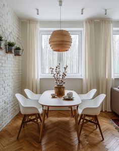 a dining room table with chairs and a vase on it in front of a window