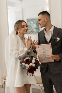 a man and woman standing next to each other in front of a table with flowers on it