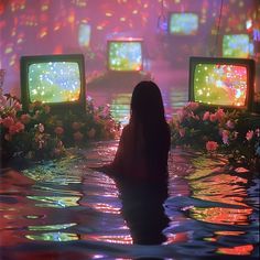 a woman sitting in the water watching tvs with flowers around her and glowing lights on them