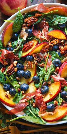 a salad with peaches, blueberries and pecans in it on a plate