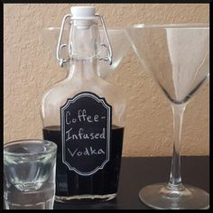 two glasses and a bottle on a table with a chalkboard label next to it