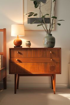 a wooden dresser with two vases and a plant on it's side table