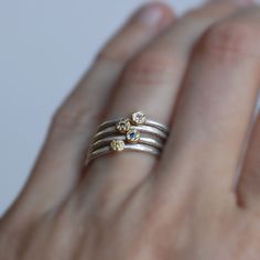 "This listing is for ONE 18k gold, diamond and sterling silver stack ring. Multiple rings are shown for diamond color reference only. Handmade 3mm 18k gold pebble set with a 1.7mm diamond of your choice. I hand forged the band from full round sterling. Simple and sweet worn alone, or stack them up for lots of sparkle! Details - Diamonds - 1.7mm - White, brown, Blue and Yellow (both blue and yellow are treated to enhance color) Band - 1.6mm Sterling Silver with hammered texture Finish - Pictured Yellow Gold Sterling Silver Stackable Rings, Dainty Sterling Silver Rings With Single Cut Diamonds, Stackable Sterling Silver Birthstone Ring Fine Jewelry, Fine Jewelry Diamond Stackable Topaz Ring, Fine Jewelry Diamond White Stackable Rings, Sterling Silver Stackable Rings With Rose Cut Diamonds, Gold Sterling Silver Birthstone Ring With Rose Cut Diamonds, Silver Yellow Sapphire Rings For Anniversary, Anniversary White Topaz Stackable Rings