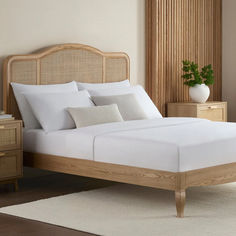 a bed with white linens and pillows in a room next to a wooden dresser