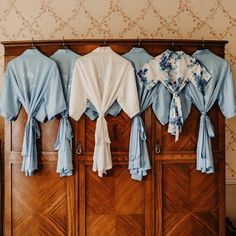 several blue and white shirts hanging on a wooden wall in a room with wood paneling