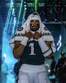 a football player wearing a towel on his head in the middle of a hallway with other people around him