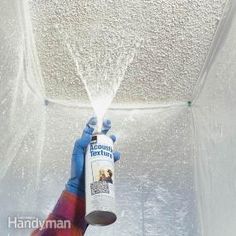 a person spraying water on the ceiling with a sprayer in their hand and wearing blue gloves