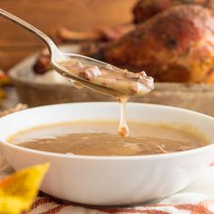 a spoon full of gravy being lifted from a bowl