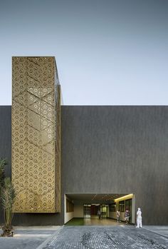 an entrance to a large building with a tall tower in the middle and palm trees on either side