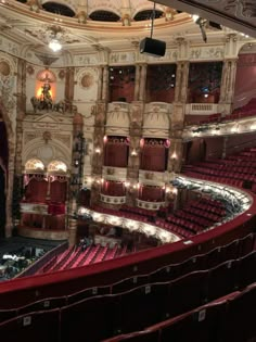 an empty theatre with red seats and chandeliers