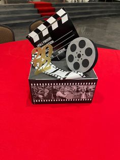 a red table topped with a box filled with film and clapsticks on top of it