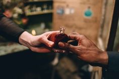 two people are holding a small bottle of wine in their hands and exchanging it with another person's hand