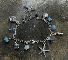 Handmade by me silver plated charm bracket with various sea themed charmed and semi precious stones including turquoise, aquamarine, flourite. Length of bracelet 20cm.  All items come wrapped in tissue and in small gift bag. Please check out my other themed charm bracelets and necklaces. Thank you Silver Charm Bracelet With Natural Stones For Gift, Handmade Silver Ocean-inspired Bracelets, Handmade Ocean-inspired Charm Bracelet As A Gift, Handmade Ocean-inspired Charm Bracelet For Gift, Handmade Ocean-inspired Charm Bracelet For Gifts, Ocean-inspired Blue Charm Bracelet For Gifts, Handmade Silver Charm Bracelet For Beach, Silver Bohemian Charm Bracelet For Beach, Bohemian Silver Charm Bracelet For Beach