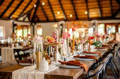 a long table with plates and vases on it in front of a wooden ceiling