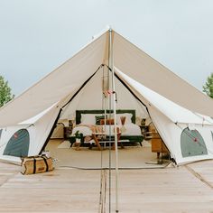 a large tent with couches and tables in the inside is set up on a wooden deck