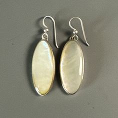 Earrings, Mother of Pearl Ovals on French wires. Sleek, Modern, Simply Classic. 2 ½" long Mother of pearl shell for jewelry refers to the nacre that coats the inside layer of the mollusk shell which is used to form pearls--hence, it's the mother of the pearl. Mother of pearl shell jewelry can include much larger focal pieces than simple pearls since nacre substance takes up a whole shell's interior, offering a larger working surface for carving. In addition to jewelry, mother-of-pearl shell has been used in medieval European, East Asian and Islamic religious art. Starting during the Victorian Era, mother-of-pearl shell began to also be used for clock faces, buttons, jewelry boxes and more. One especially popular use was inlay work, such as the handles of knives and pistols, as well as hist Classic Oval High Luster Pearl Earrings, White Oval Earrings With Polished Finish, Silver Shell-shaped Earrings With Pearl Drop, Elegant Oblong Jewelry With Ear Wire, Oval Mother Of Pearl Jewelry For Formal Occasions, Oval Mother Of Pearl Jewelry For Formal Events, Oval Pearl Drop Jewelry, Elegant Mother Of Pearl Shell Earrings, Elegant Oval White Jewelry With Mother Of Pearl