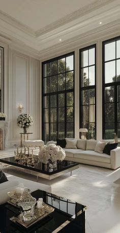 a living room filled with lots of white furniture and large windows in the wall behind it