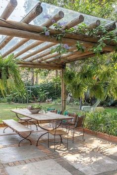 an outdoor dining area with table, chairs and pergolated roof in the background