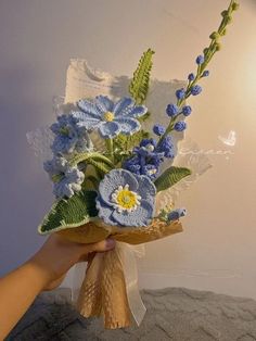 a hand holding a bouquet of blue flowers