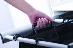 a person holding onto the handle of a black bag with white handles and straps on it