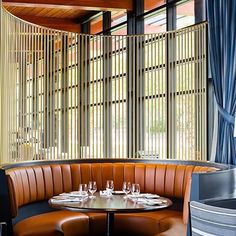 a restaurant booth with two round tables and four chairs, along with blue drapes on the windows