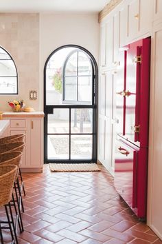 a kitchen with an arched window and tiled flooring next to a red refrigerator freezer