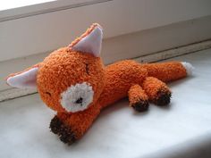 an orange stuffed animal laying on top of a window sill