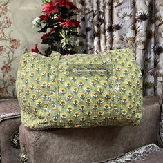 a large green bag sitting on top of a chair next to a flower pot and curtain