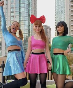 three young women dressed in colorful outfits posing for the camera with their arms up and legs crossed