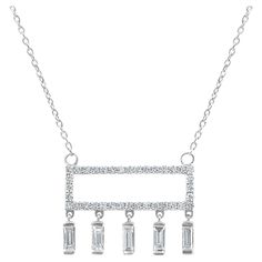 This contemporary necklace is crafted from 18K white gold, offering a sleek and modern aesthetic. The piece is distinguished by its geometric design, featuring a horizontal rectangle pavé-set with round diamonds totaling 0.29 carats. This creates a sparkling bar that serves as the centerpiece of the necklace. Dangling elegantly from this diamond-encrusted bar are five baguette-cut diamonds, collectively weighing 0.36 carats. The baguette diamonds are known for their clarity and crisp lines, whic Refraction Of Light, Contemporary Necklace, White Gold Chains, Baguette Diamonds, Round Necklace, Baguette Cut Diamond, Modern Necklaces, Baguette Cut, Baguette Diamond