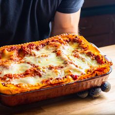 a casserole dish with meat and cheese in it sitting on a wooden table