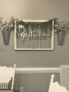 the dining room table is set for two with white chairs and vases filled with flowers