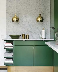 a kitchen with green cabinetry and gold fixtures on the wall, along with marble counter tops