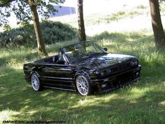 a black convertible car parked in the grass