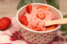 a bowl filled with ice cream and strawberries on top of a pink polka dot table cloth