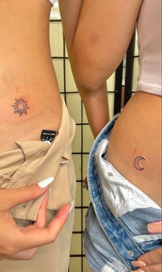 two women with small tattoos on their stomachs, one is holding a cell phone