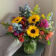 a vase filled with lots of colorful flowers on top of a table next to a couch