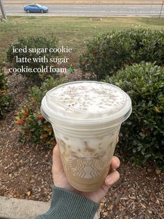 someone holding up a cup of iced sugar cookie latte