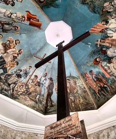 a large painting on the ceiling of a building with a cross in front of it