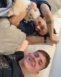 a man and woman laying on a couch with a small white dog in their lap