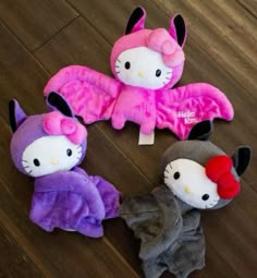 three hello kitty stuffed animals laying on top of a wooden floor