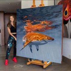 a woman standing next to a painting of a shark in the ocean with orange and blue colors